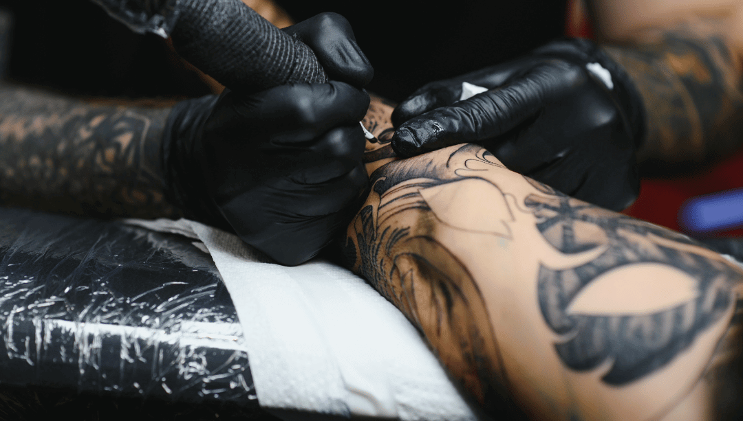 Tätowierer arbeitet mit Pen-Maschine an Blackwork-Tattoo am Unterarm